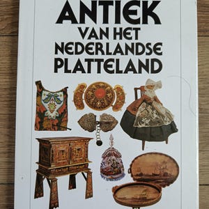 Puede incluir: Una portada de libro blanca titulada Antiek van het Nederlandse Platteland por Noortje de Roy van Zuydewijn. La portada presenta ilustraciones de un textil con cuentas, joyas de oro, una muñeca con ropa tradicional, un gabinete de madera y dos bandejas ovaladas.