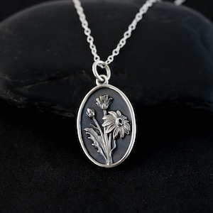 a silver necklace with a picture of flowers on it