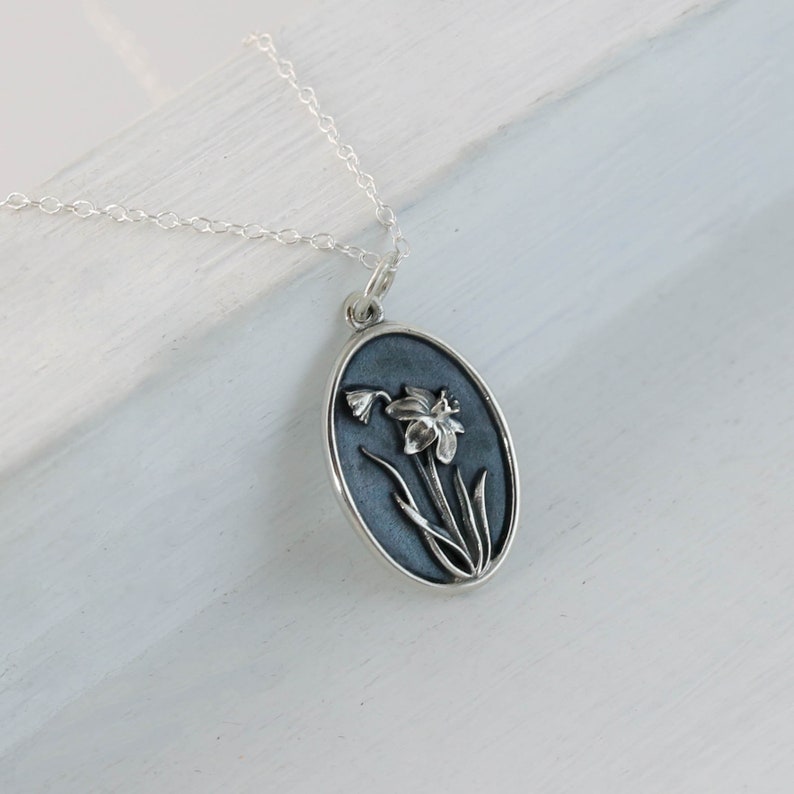 a silver necklace with a picture of a flower on it