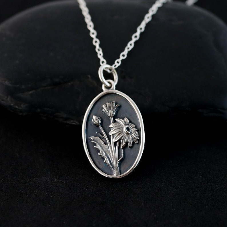a silver necklace with a picture of flowers on it