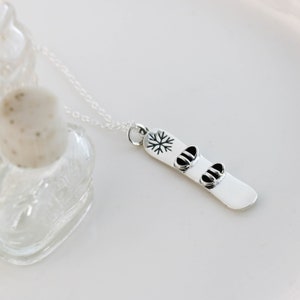 a silver necklace with two snowboard charms on it
