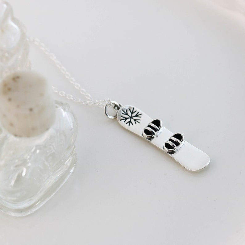 a silver necklace with two snowboard charms on it