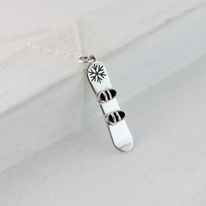 a silver necklace with a snowboard on it
