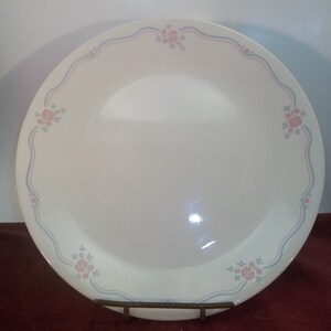 Può includere: Un piatto da portata in ceramica bianca con un motivo floreale blu e rosa. Il piatto ha un bordo smerlato.