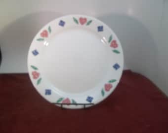Puede incluir: Plato de cena de cerámica blanca con un diseño floral azul, verde y rosa alrededor del borde.