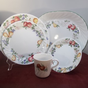 Puede incluir: Un juego de vajilla de cerámica blanca con un diseño de frutas y flores. El juego incluye una fuente ovalada grande, un plato para cenar, un plato para ensalada y una taza.