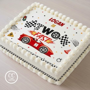 May include: A rectangular sheet cake with white frosting and a racing-themed edible topper. The design features a red race car with the number 2, checkered flags, flames, and the text Logan is two fast. Small icons include a traffic light and cone.