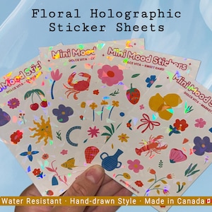 May include: Floral holographic sticker sheets with colorful floral and whimsical designs. Each sheet features various illustrations, including flowers, fruits, and sea creatures. The text on the sheets reads "Mini Mood Stickers".