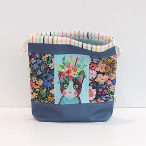 May include: A white ceramic mug with a black handle and the text "But First, Coffee" in a black, bold font. The mug is on a white surface.