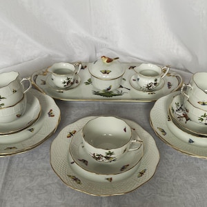 May include: A complete porcelain tea set with a white background, featuring cups, saucers, a sugar bowl, a creamer, and a serving tray. The set is decorated with butterfly and bird motifs, and gold trim.