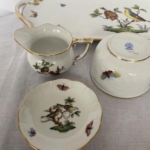 May include: A white porcelain serving set with gold trim, featuring hand-painted birds and butterflies. The set includes a serving tray, creamer, bowl, and small dish. The tray measures approximately 16 inches long.