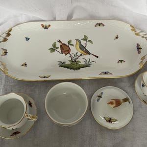 May include: A white porcelain serving platter and matching dishware set. The platter features a bird and butterfly design with gold trim. The set includes a creamer, sugar bowl, and covered dish, all with coordinating bird and butterfly motifs.