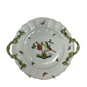 May include: White ceramic serving dish with a scalloped edge and two green handles. The dish features a detailed illustration of two birds perched on a branch, surrounded by butterflies. The rim has a textured, woven pattern.