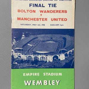 May include: A vintage football program from the 1958 Football Association Challenge Cup Final Tie between Bolton Wanderers and Manchester United. The program features a stadium illustration and text, including "Empire Stadium Wembley" and "Official Programme."