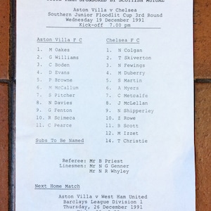 May include: A black and white printed document with the title "Youth Team Sponsored by Scottish Mutual" and lists the Aston Villa and Chelsea football teams with their players' names and numbers. The document also includes the date and time of the match, the referee and linesmen's names, and information about the next home match.