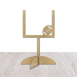 May include: A gold glitter football goalpost with a football resting on the top crossbar. The goalpost is on a light wood surface.