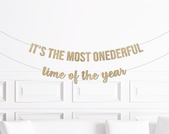 Könnte beinhalten: Goldene Glitzergirlande mit dem Text "It's the most onederful time of the year".