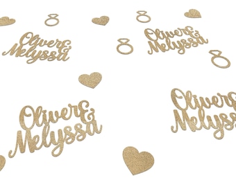 Peut inclure: Confettis dorés à paillettes avec les noms "Oliver & Melyssa", des cœurs et des formes d'anneaux. Les noms sont écrits en cursive. Les confettis sont dispersés sur un fond blanc, idéal pour les mariages ou les fiançailles.