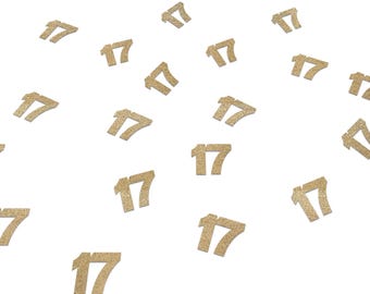 May include: Gold glitter number 17 cutouts scattered on a white background. The numbers are in a serif font and appear to be three-dimensional. Ideal for birthday or anniversary decorations.