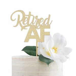 May include: Gold glitter cake topper with the text "Retired AF" on a white cake with a white flower.