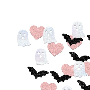 May include: A scattering of Halloween-themed confetti on a white background. The confetti includes glittery white ghosts, pink hearts, and black bats. The shapes are scattered across the frame, creating a festive and playful design.