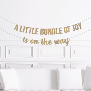 May include: A gold glitter banner that reads "A little bundle of joy is on the way".