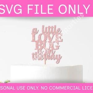 May include: A pink glitter cake topper with the words "a little LOVE BUG is on the way" on a white cake. The top banner reads "SVG FILE ONLY" and the bottom banner reads "PERSONAL USE ONLY. NO COMMERCIAL LICENSE."