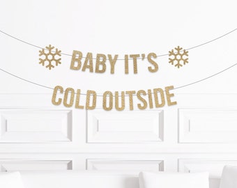 May include: Gold glitter banner with the text "Baby It's Cold Outside" and two snowflake accents.