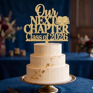 以下が含まれることがあります： 金色の葉のアクセントが付いた3段の白いケーキ。ケーキの上には「Our Next Chapter Class of 2026」と本のイラストが描かれた金色のグリッターケーキトッパーが飾られています。ケーキは金色のケーキスタンドに載っています。