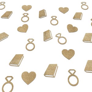 May include: Gold glitter confetti in the shape of engagement rings, hearts, and books scattered on a white background. The confetti is a warm gold color, and the shapes are clearly defined. Ideal for wedding or engagement celebrations.