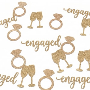 May include: A collection of gold glitter confetti pieces featuring the word engaged in cursive script, diamond engagement ring shapes, and pairs of champagne flutes. These decorative cutouts are made of a sparkling gold material.