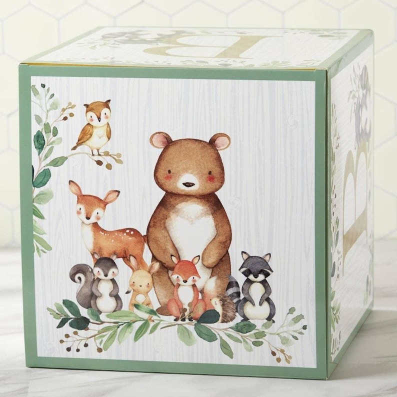 May include: A square box with a woodland animal design. The box features a brown bear, deer, fox, squirrel, raccoon, owl, and other forest creatures. The box has a green border and a light wood grain background.