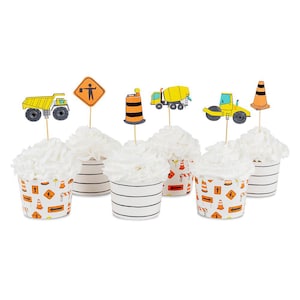 May include: Cupcakes with white frosting and construction-themed toppers. The toppers include a yellow dump truck, a road sign, an orange and black traffic cone, a cement mixer, a road roller, and a traffic cone. The cupcake liners have a construction design.
