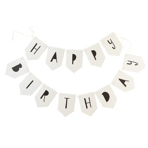May include: A white banner with black letters spelling "HAPPY BIRTHDAY". The banner is made of individual pennants strung together with a thin, off-white string. Each pennant is a light cream color with a black letter.