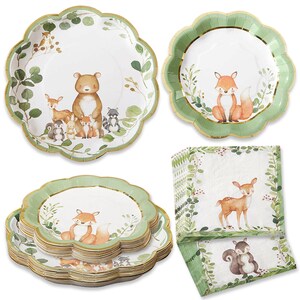 May include: A collection of woodland-themed party supplies, including scalloped-edge paper plates and napkins. The plates feature illustrations of forest animals like bears, foxes, and deer, with a green and gold border. The napkins also have animal and leaf designs.