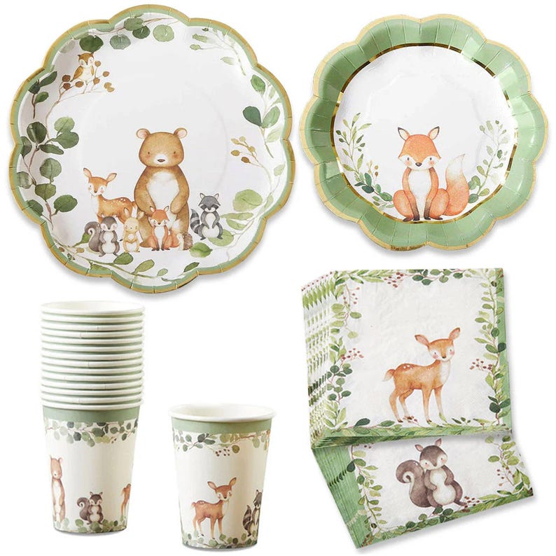 May include: A collection of woodland-themed party supplies. Includes plates with scalloped edges, cups, and napkins. The plates feature illustrations of a bear, fox, deer, and other forest animals. The color palette is primarily white, green, and gold.