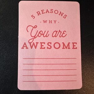 K&ouml;nnte beinhalten: Eine rosa Karte mit abgerundeten Ecken zeigt den Text "5 REASONS - WHY - You are AWESOME" in Rot. Darunter befinden sich f&uuml;nf horizontale Linien zum Schreiben. Die Karte liegt auf einer dunklen Oberfl&auml;che.
