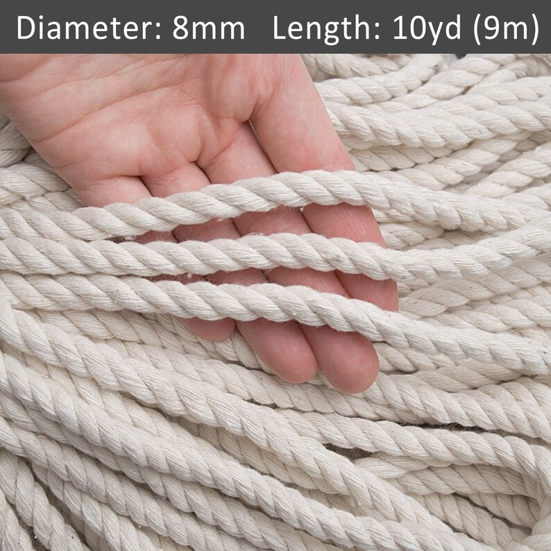 K&ouml;nnte beinhalten: Nahaufnahme eines wei&szlig;en Baumwollseils mit einem Durchmesser von 8 mm und einer L&auml;nge von 10 Yards (9 Metern). Das Seil wird in einem Stapel gezeigt, wobei eine Hand ein paar Str&auml;nge h&auml;lt.