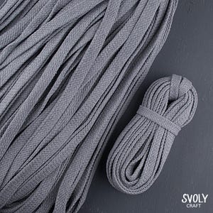 May include: Gray flat braided cord, ideal for crafting and DIY projects. The image shows a large pile of the cord, along with a neatly coiled bundle. The cord has a textured surface and is suitable for various creative applications.