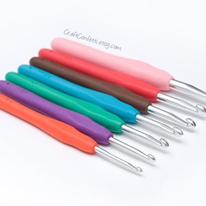May include: Set of seven colorful crochet hooks with metal hooks and plastic handles. The hooks are arranged in a row from largest to smallest. The colors are pink, red, brown, teal, green, purple, and orange.