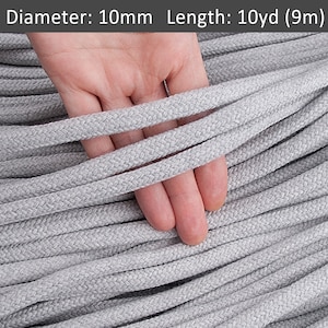 May include: A close-up of a grey cotton cord, 10mm in diameter and 10 yards (9 metres) long. The cord is shown in a pile with a hand holding a few strands.