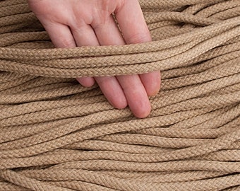 Puede incluir: Primer plano de un gran paquete de cuerda de yute marrón natural. La cuerda tiene un diámetro de 8 mm y una longitud de 10 yardas (9 metros).