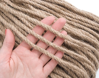 May include: A close-up of a hand holding a coil of natural brown jute rope. The rope is 6mm in diameter and 10 yards (9 meters) long.