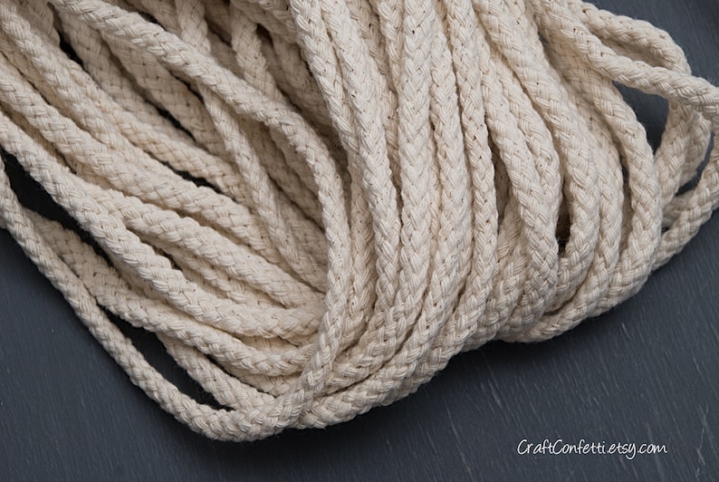 May include: A close-up of a thick, natural-coloured cotton rope. The rope is braided and has a soft, textured surface.