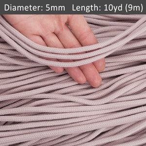 May include: A close-up of a pile of light pink cotton cord, with a hand holding a few strands. The cord is 5mm in diameter and 10 yards (9 metres) long.