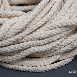 May include: Close-up of a thick, natural-coloured cotton rope. The rope is braided and has a soft, textured surface.