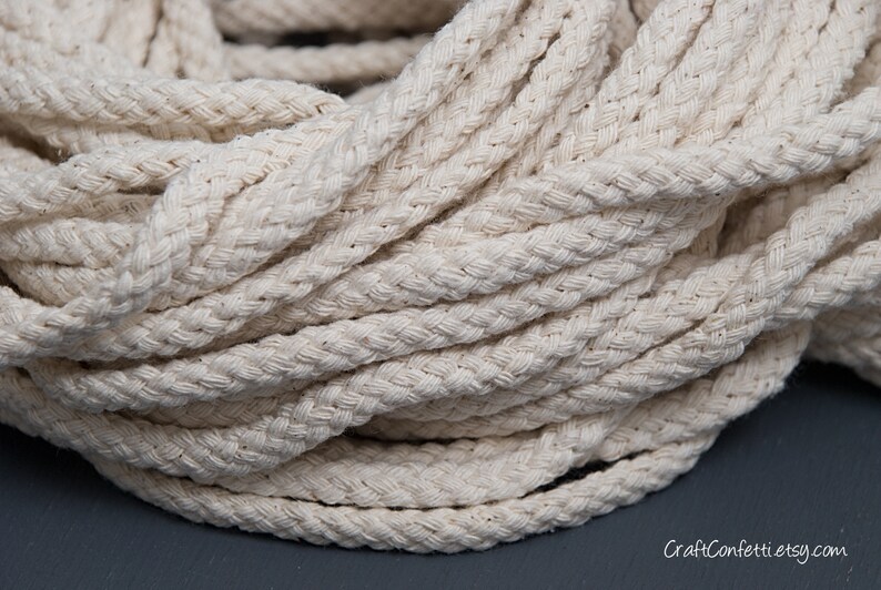 May include: Close-up of a thick, natural-coloured cotton rope. The rope is braided and has a soft, textured surface.
