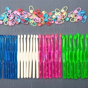 May include: A collection of colorful crochet hooks in blue, white, pink, and green. The hooks are arranged in rows on a dark gray surface. CraftConfetti.etsy.com is printed below the hooks.
