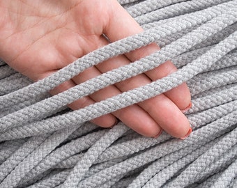 May include: Grey cotton cord, 8mm in diameter, with a length of 10 yards (9 metres). A hand is holding the cord to show its thickness.