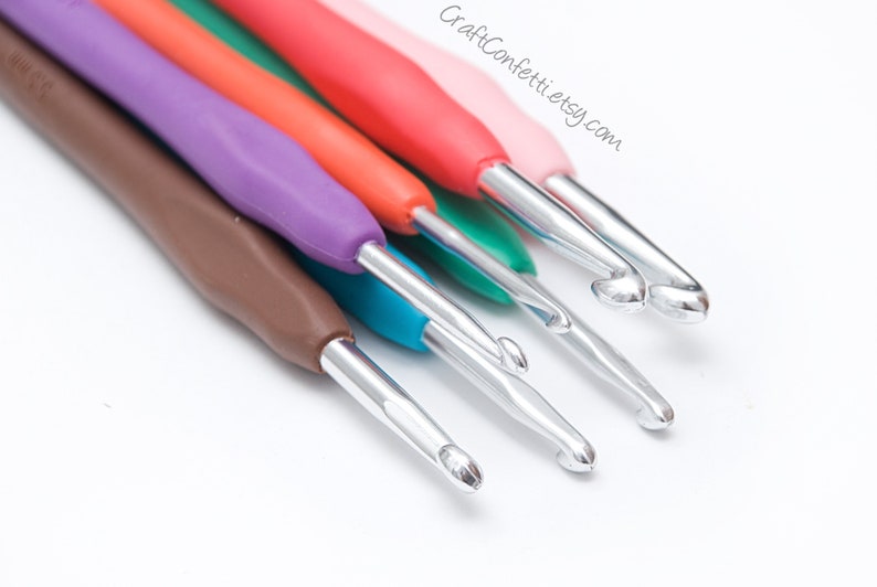 May include: A set of six colorful crochet hooks with silver metal hooks. The hooks are arranged in a row, with the largest hook at the top and the smallest hook at the bottom. The hooks are made of plastic and have a smooth, comfortable grip.
